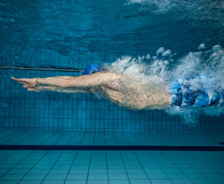 Young man swimming in pool. Concept of healthy lifestyle. Underwater photography